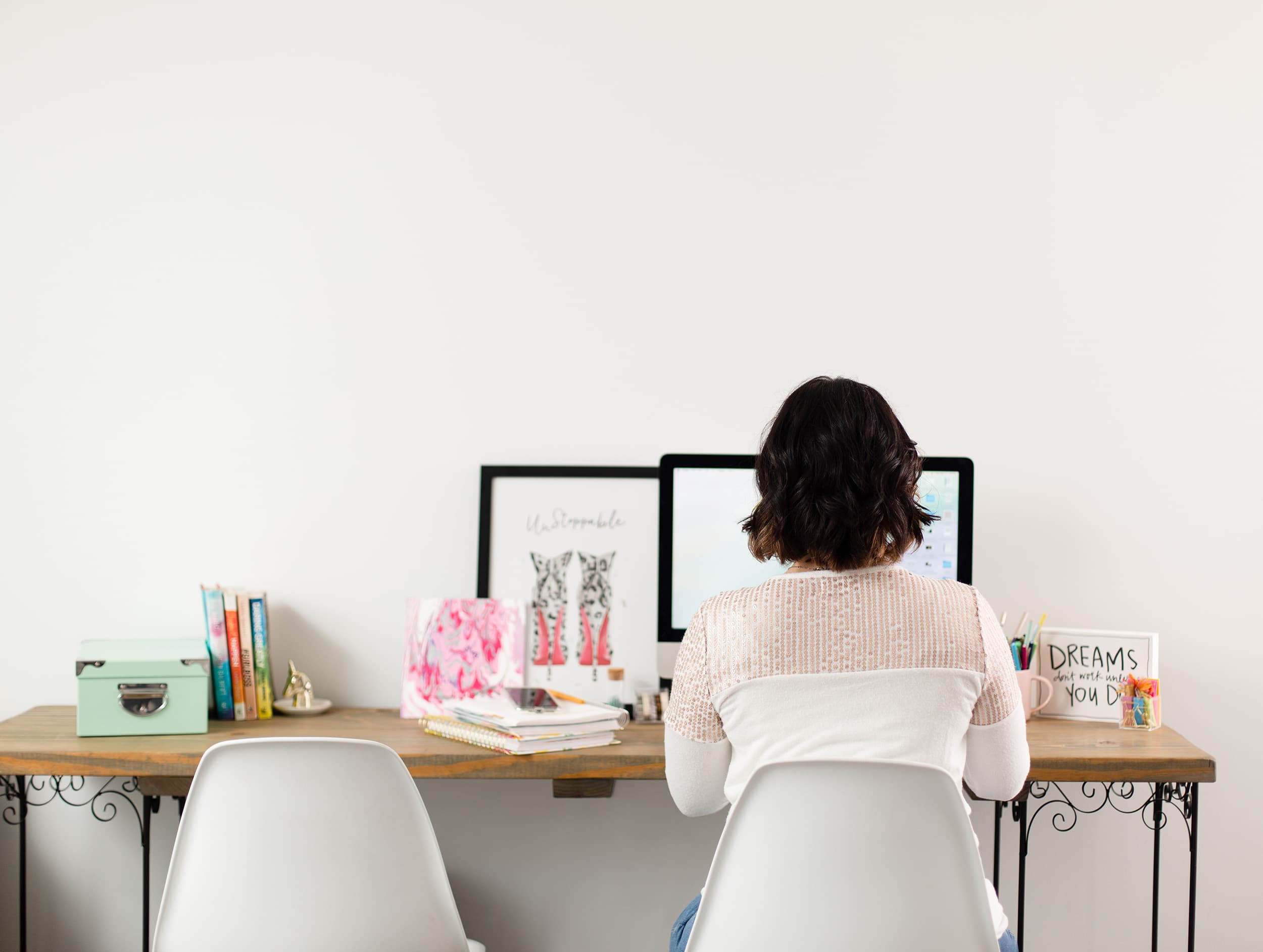 A view of Megan from behind as she types on her iMac